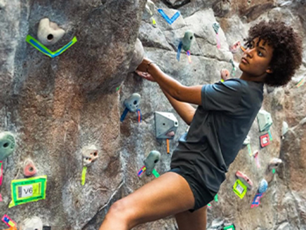 An image of Kyla hanging onto a rock climbing wall.