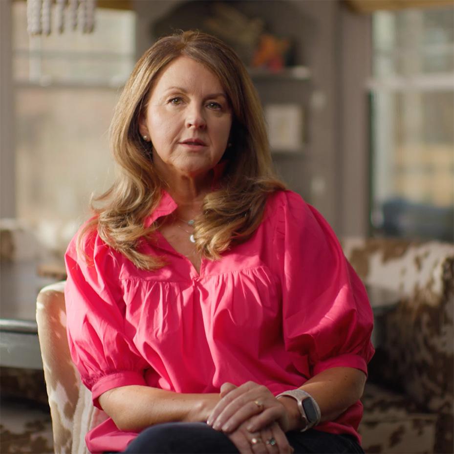 An image of Kerri Rhodes sitting in a chair wearing a pink shirt.