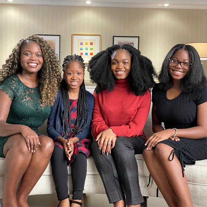 An image of Mapillar Dahn and her three children sitting on a couch while smiling at the camera.
