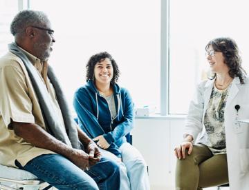 An image of two people sitting in a doctor's office having a discussion with the doctor