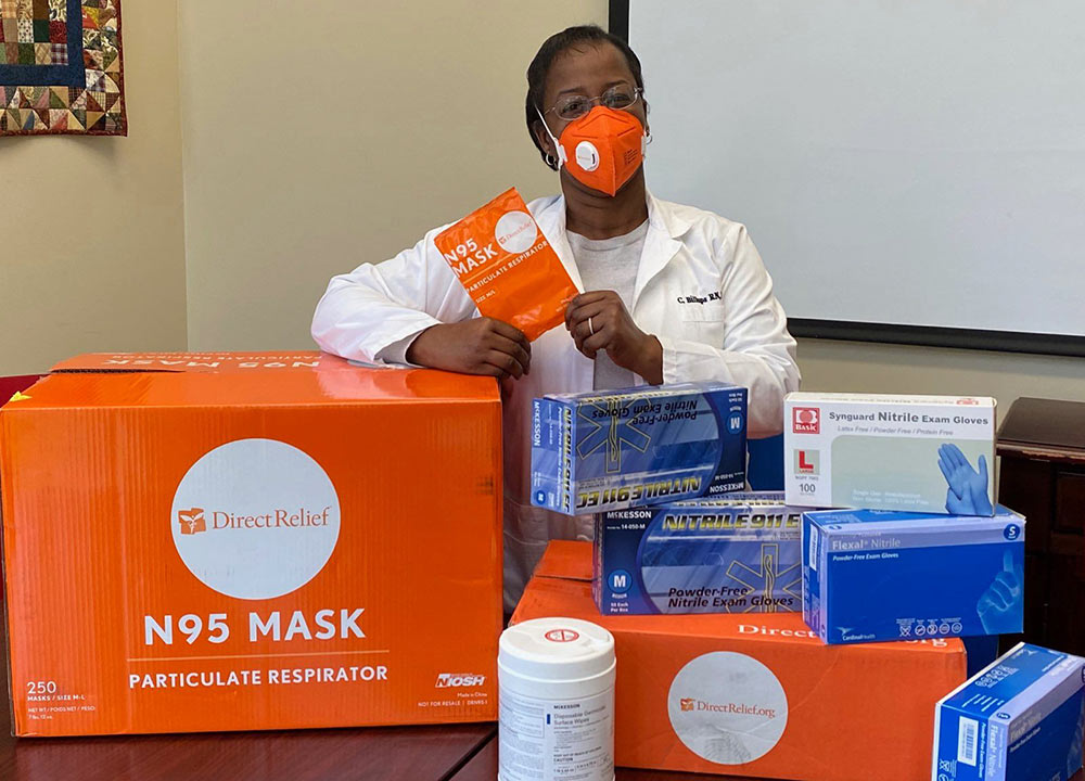 A healthcare worker poses with a donation of personal protective equipment
