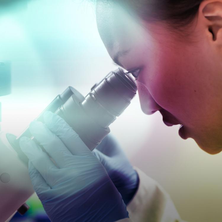 Female scientist in lab looking into a microscope