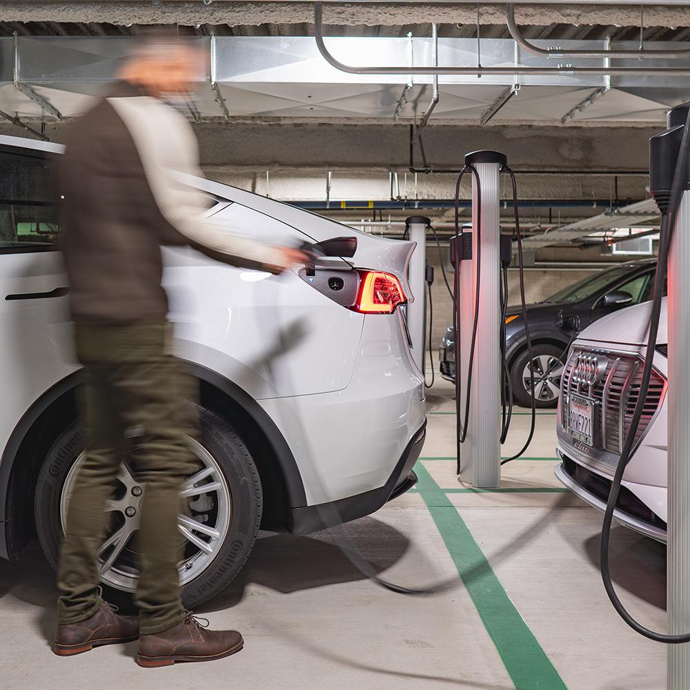 man charging electric car in garage