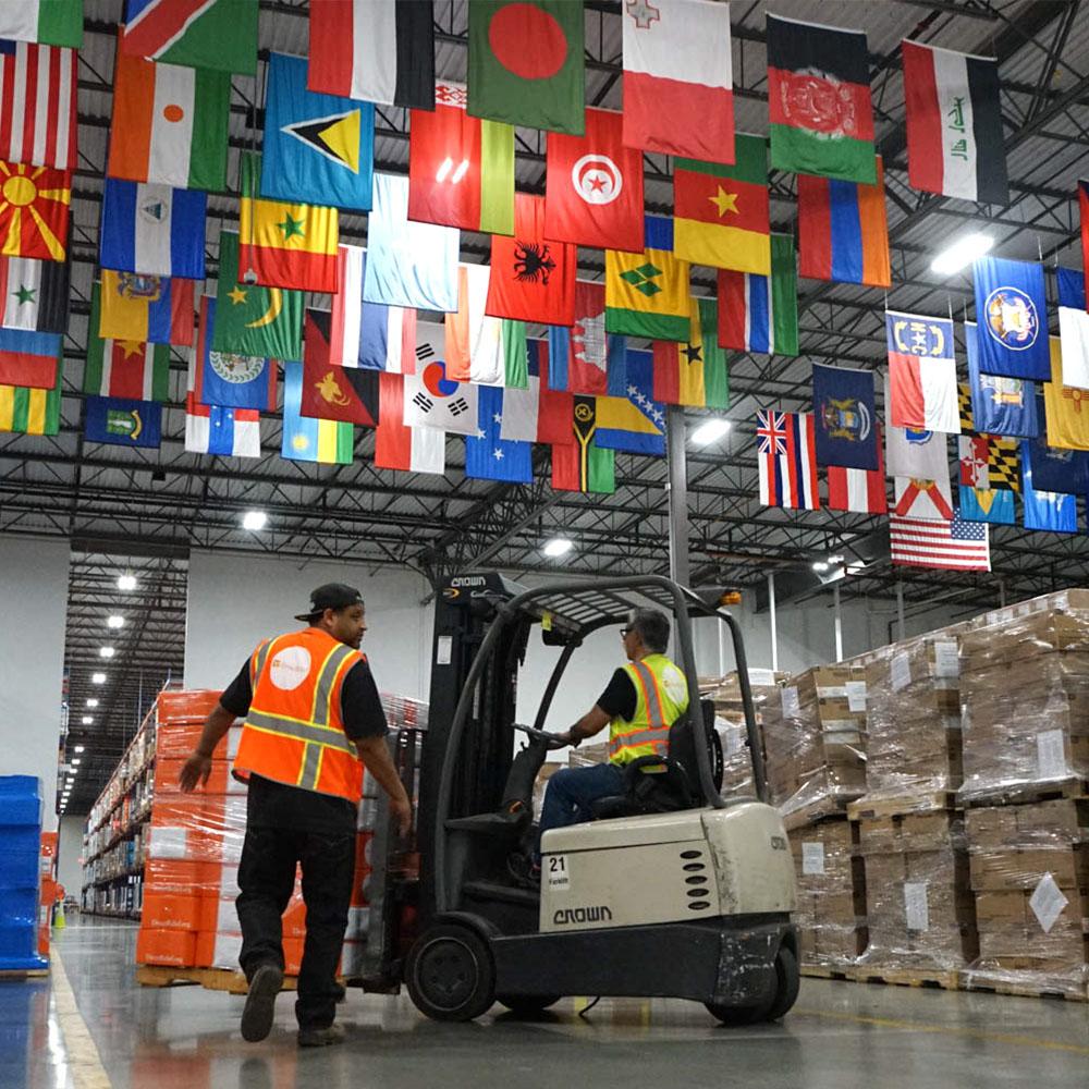 Image of workers in a warehouse with the flags of many countries hanging overhead