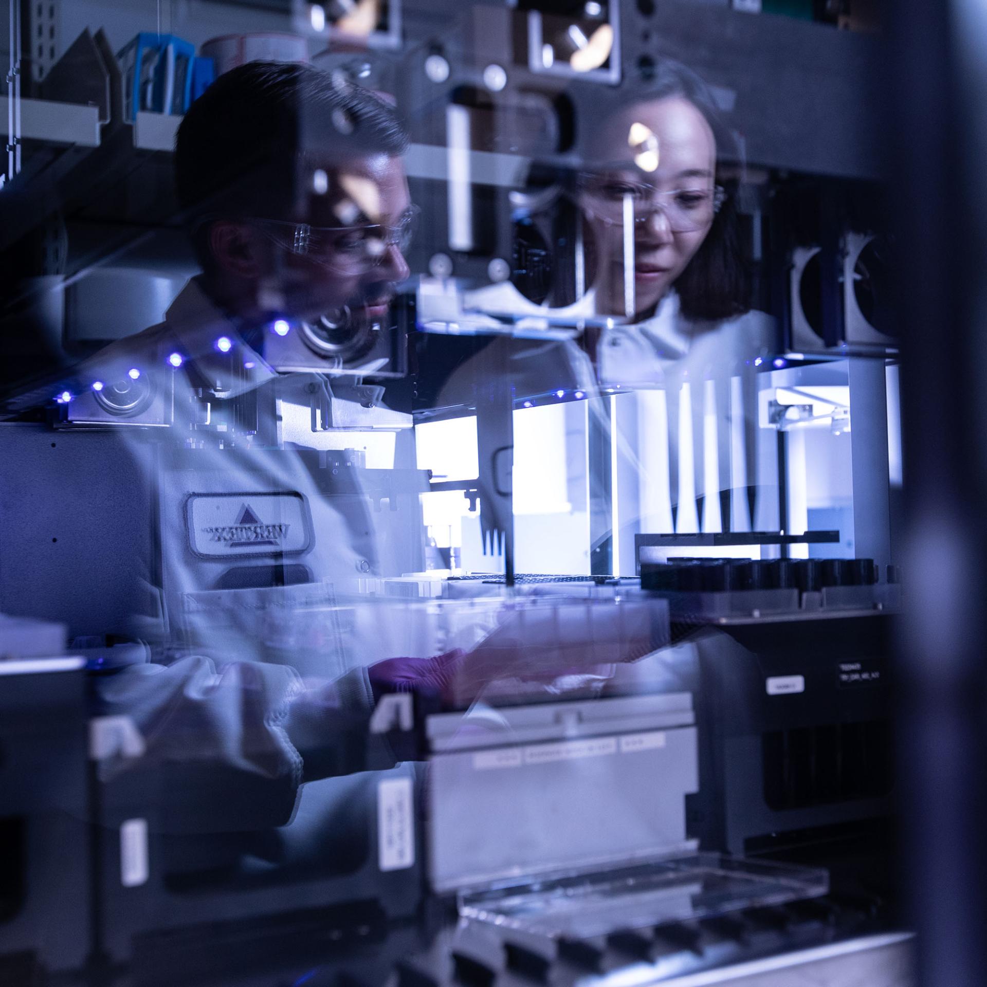 reflection of 2 scientists in a lab window