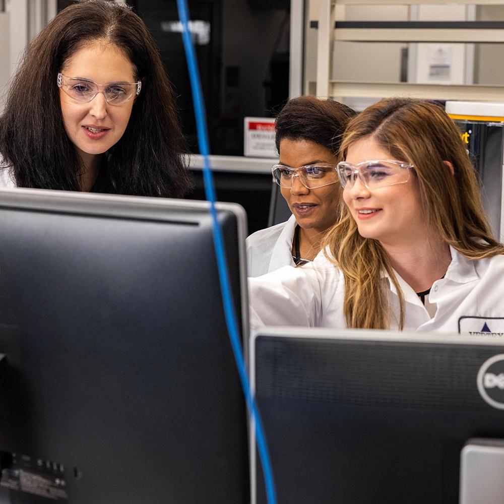 3 Vertex employees sitting at a computer smiling and discussing what's on screen