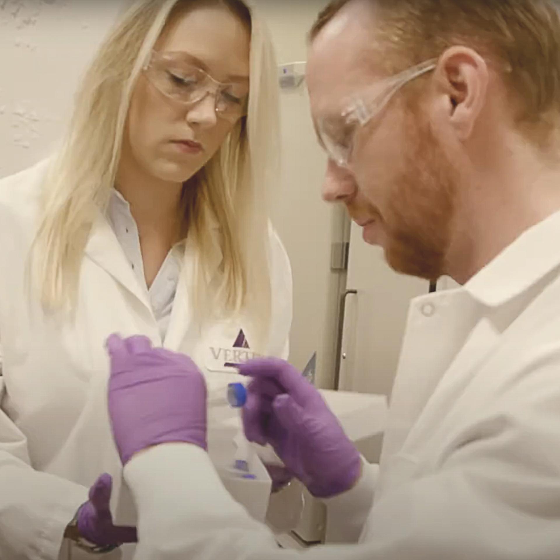 Two Vertex employees in labcoats working together