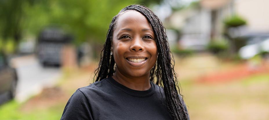 An image of Sharron Rouse wearing a black shirt standing outside smiling at the camera