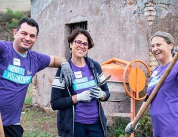 An image of 3 Vertexians in purple shirts holding garden tools