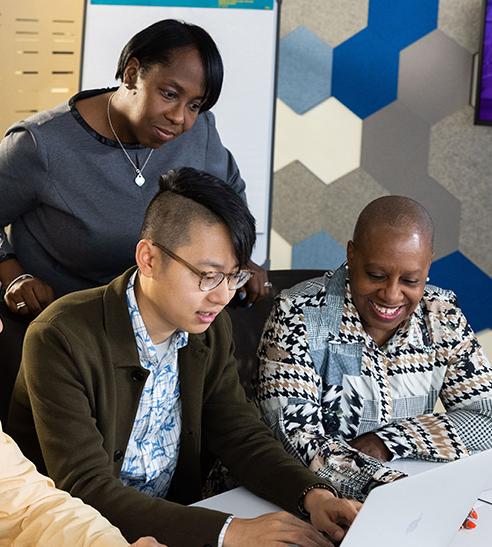 A group of 4 Vertex employees viewing content on a laptop