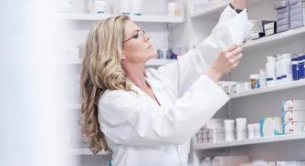 A pharmacist reaching for an item on a shelf in the pharmacy