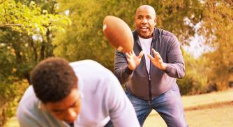 A father and son playing football in a park