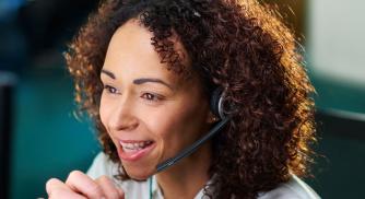 Image of a woman using a phone headset while at a computer