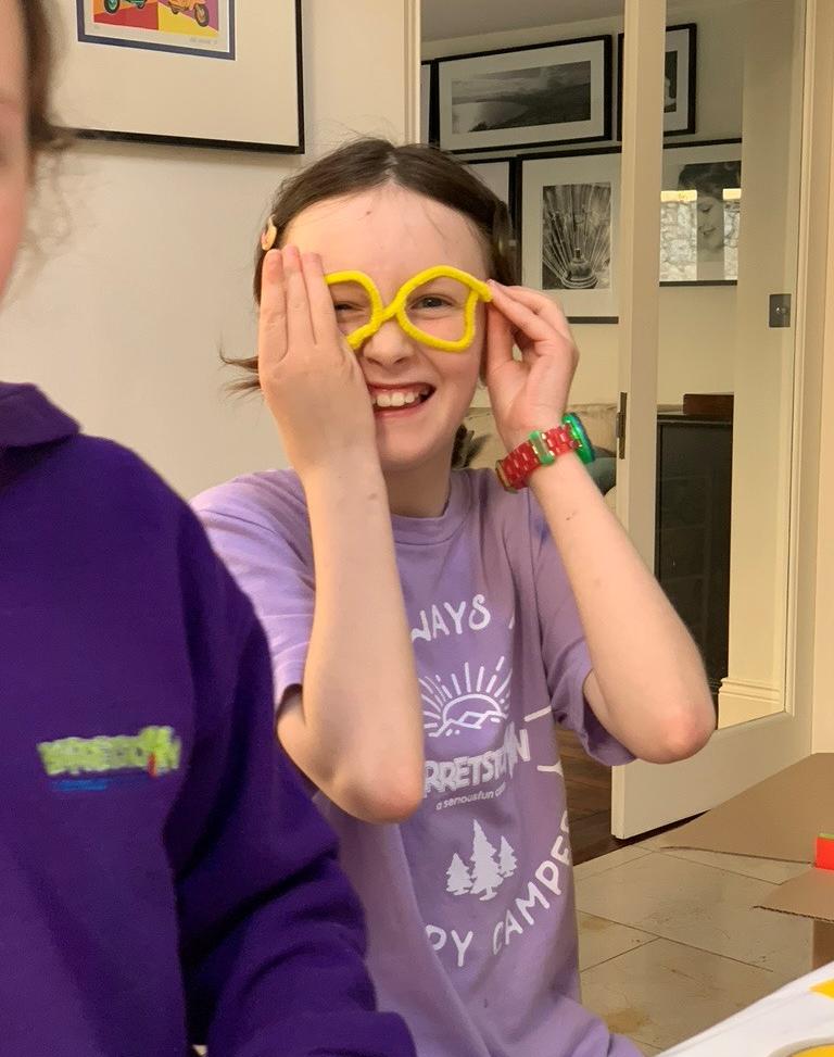 A young girl laughing, putting on yellow star shaped glasses