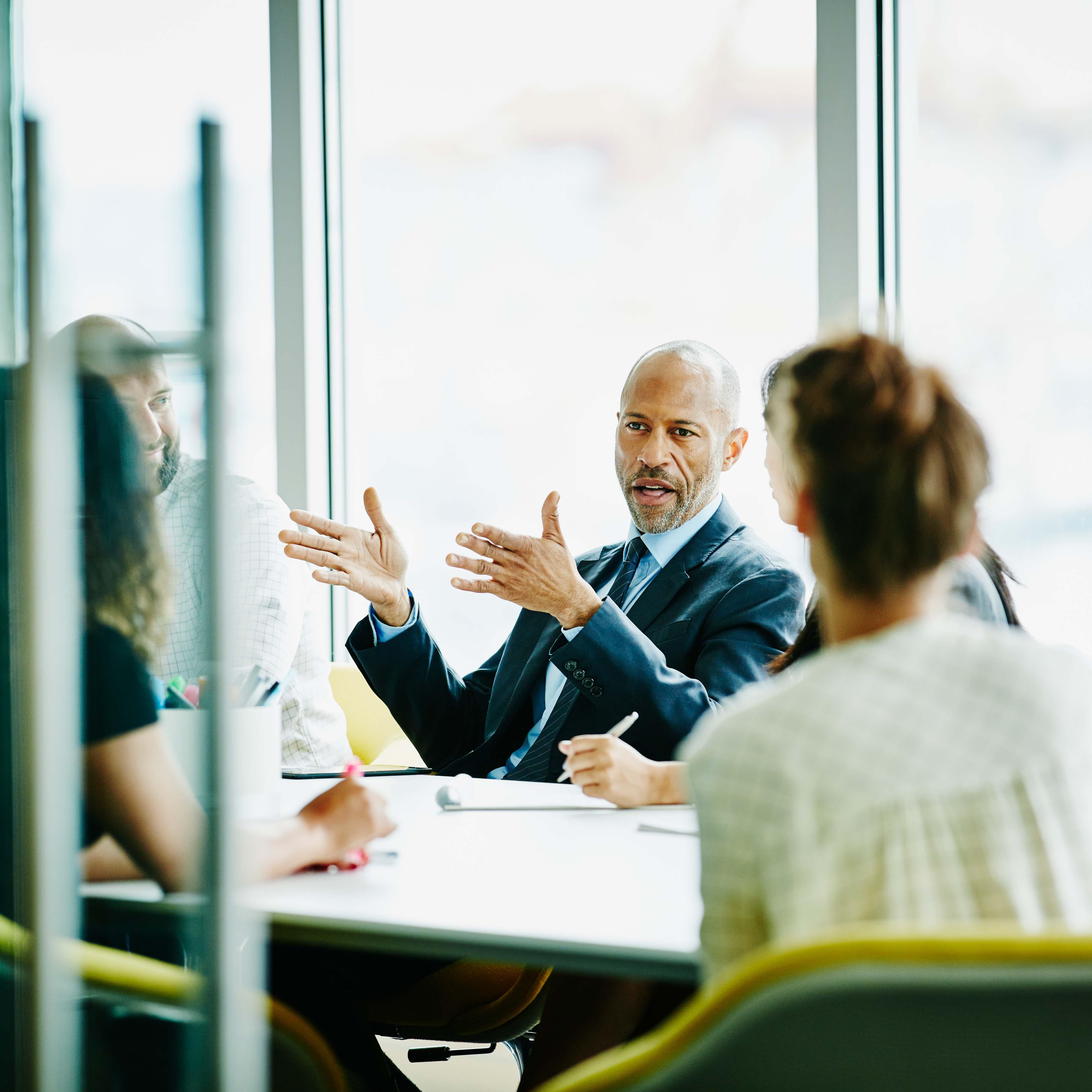 A group of office workers sitting around a table in a conference room