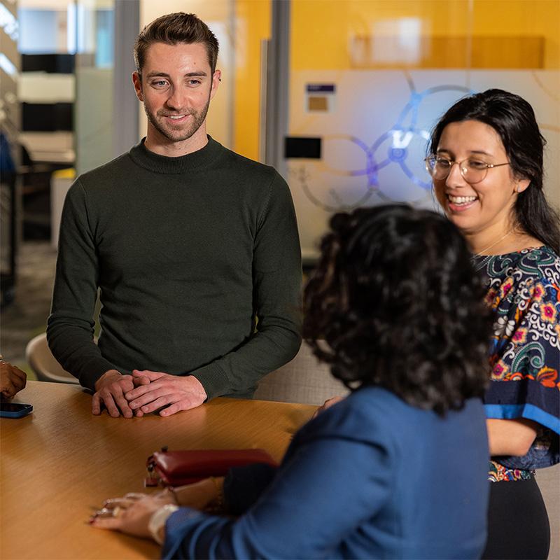 An image of three Vertexians sitting around a table smiling at one another while they have a conversation