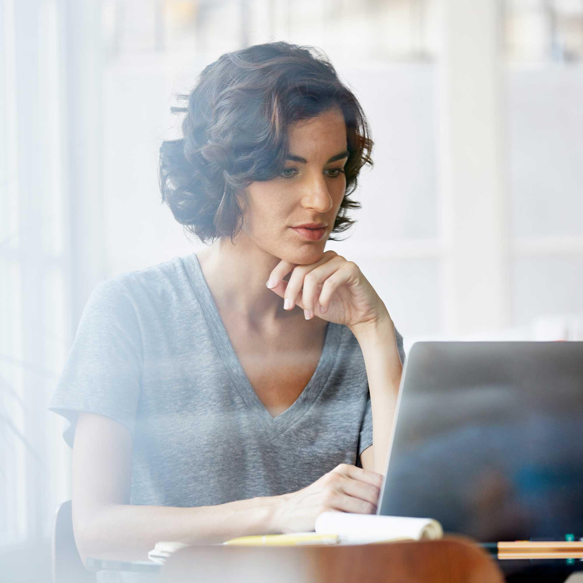 A woman sitting down working on her laptop computer