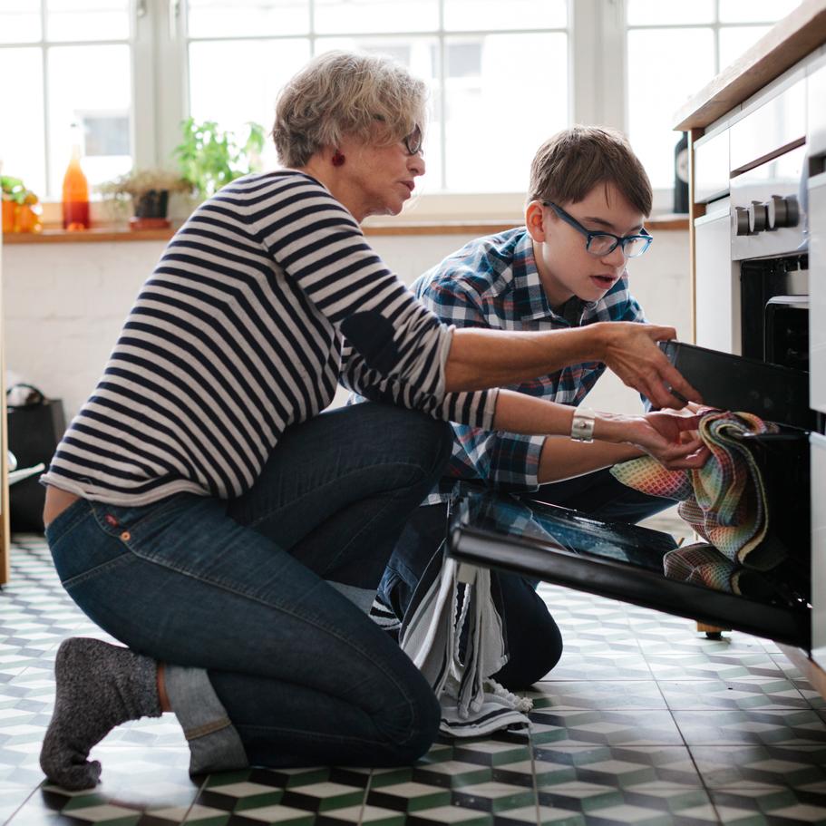 A grandmother and grandson take a pan out of the oven together