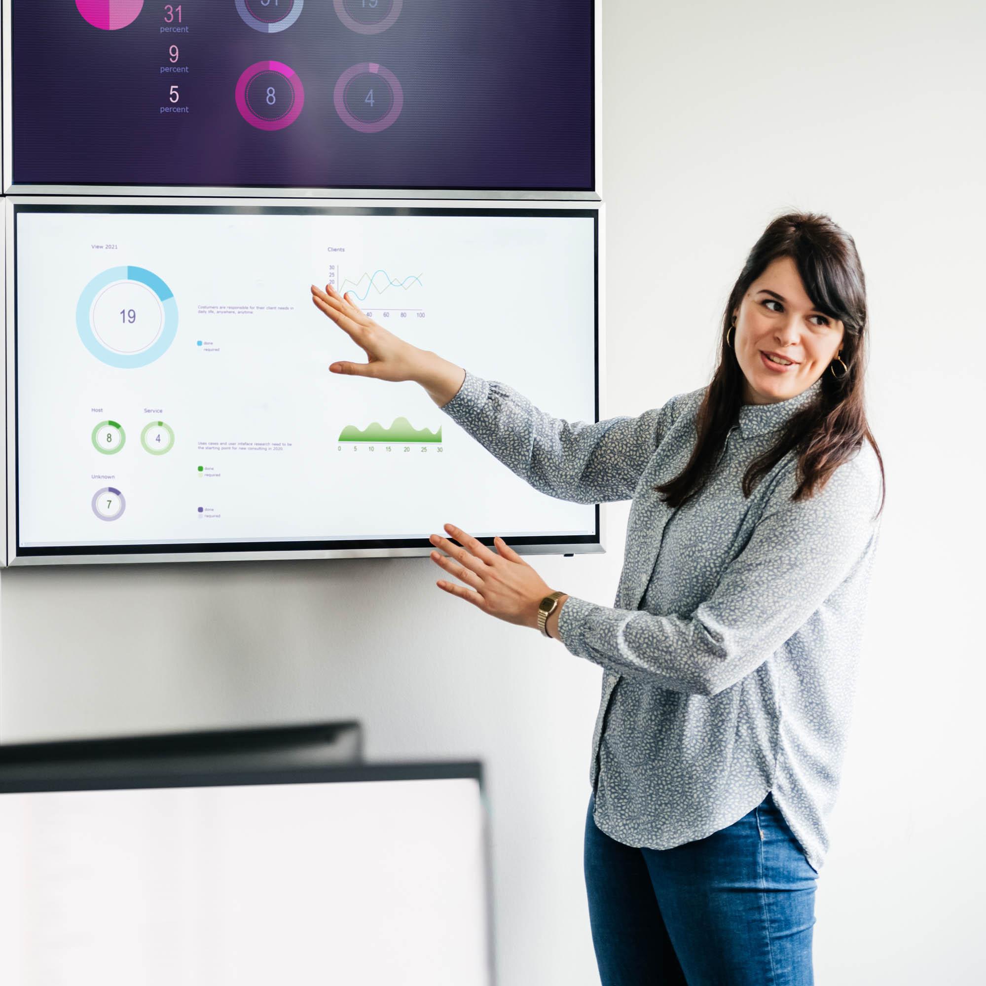 An image of a woman standing up referencing charts and graphics on a board