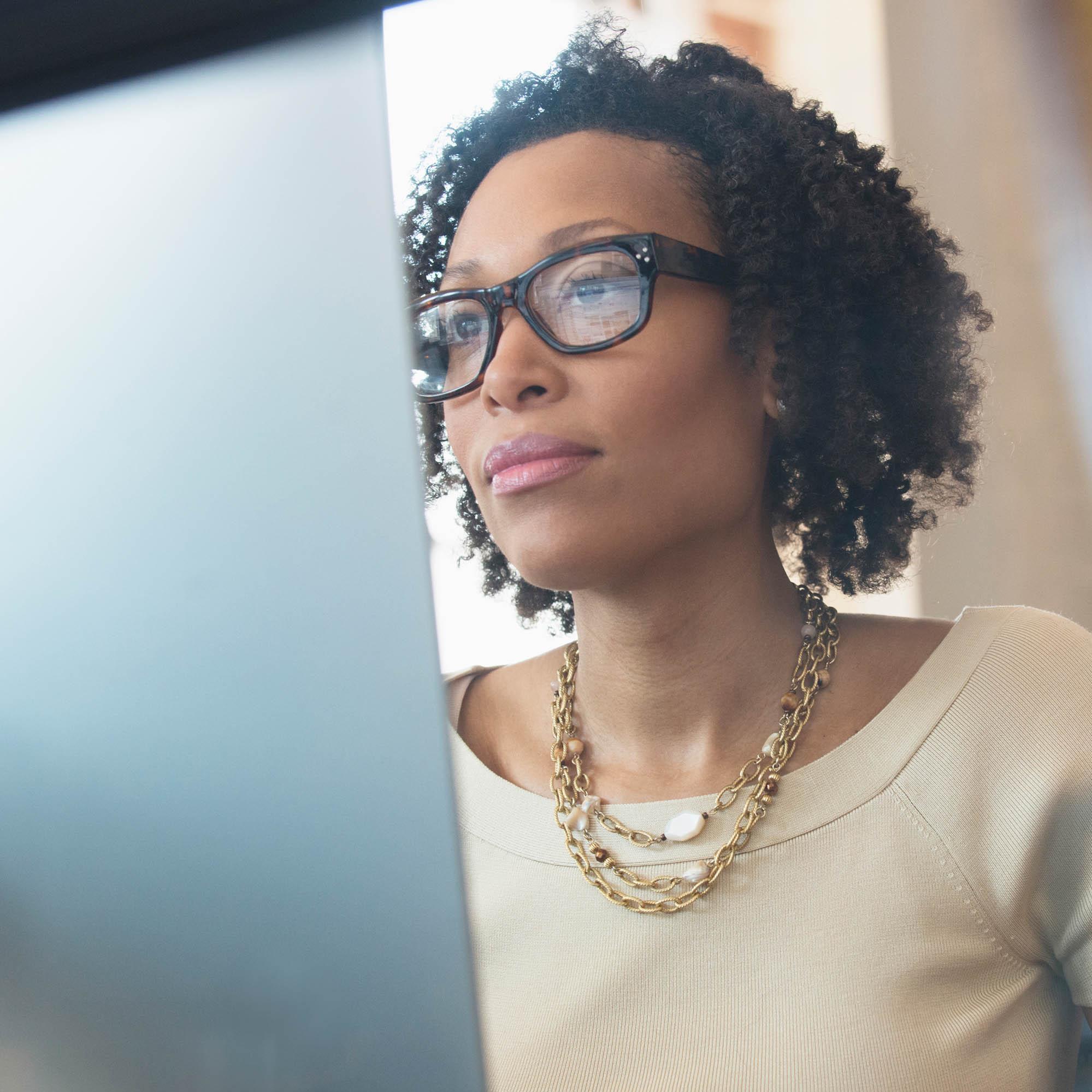 An image of a woman sitting in front of a computer monitor