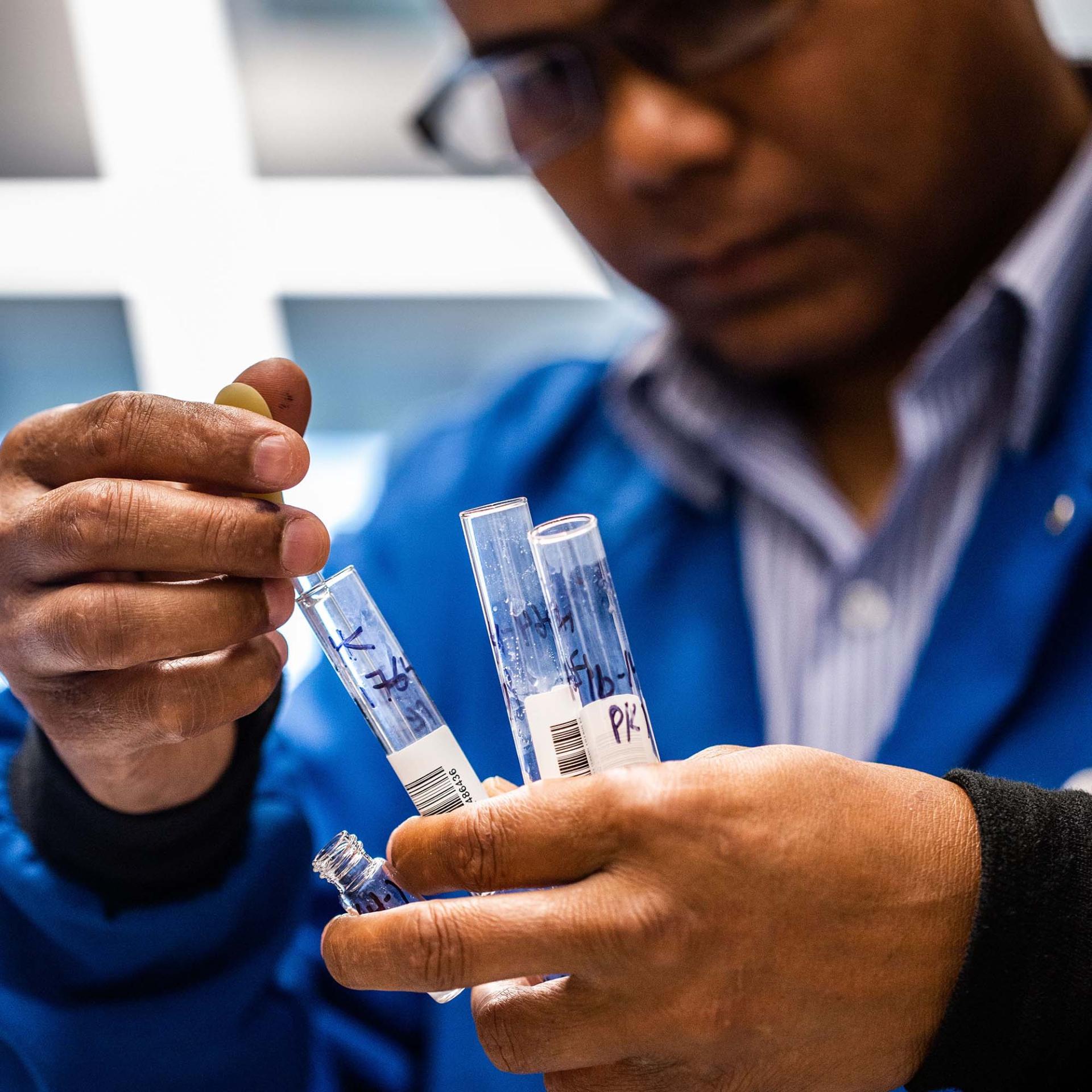 A Vertex scientist holds several vials in his hand while examining them