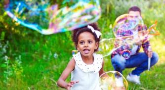 une petite fille courant apres une bulle de savon