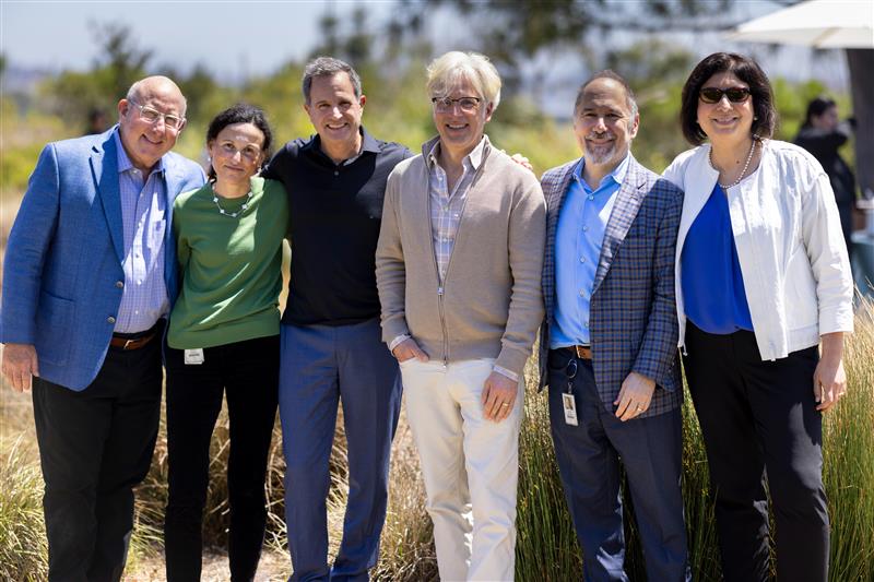 An image of Jeffery Leiden, Sabine Hadida, Paul Negulescu, Fred Van Goor, David Altshuler, and Reshma Kewalramani smiling at the camera while they stand outside in the sun at the San Diego Breakthrough Prize event.