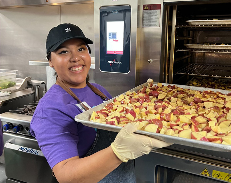 An image of a Vertexian holding up a tray of food as she volunteers in the 2023 Day of Service