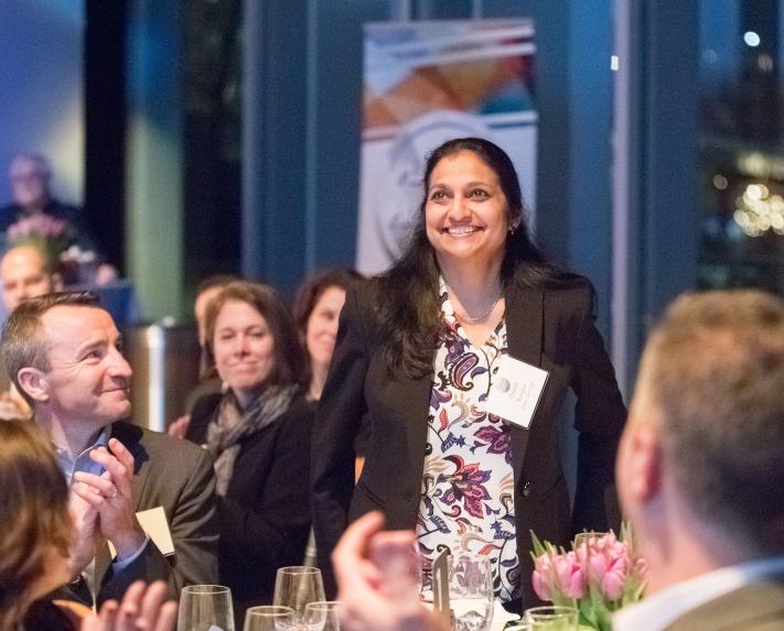 A Vertex employee standing up while others applaud around her