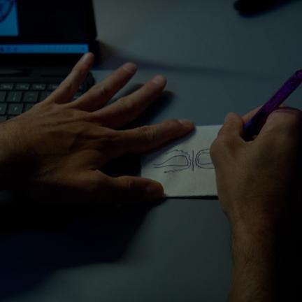 An image of a person’s hands as they draw on a napkin