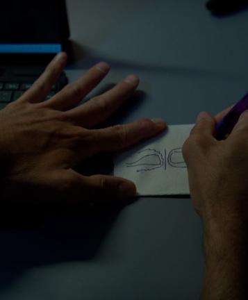 An image of a person’s hands as they draw on a napkin