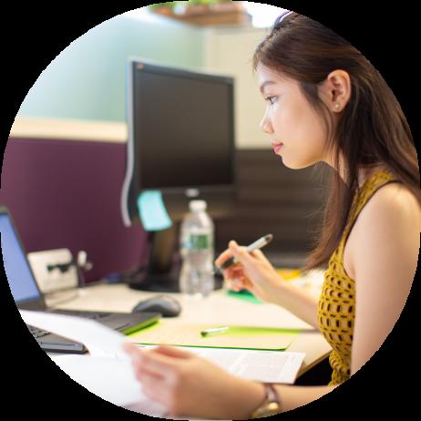 A young woman working on a laptop in a cubicle