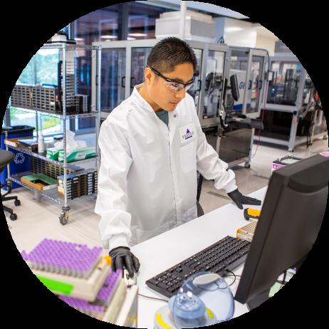 A Vertex scientist in the lab standing at a computer using the mouse