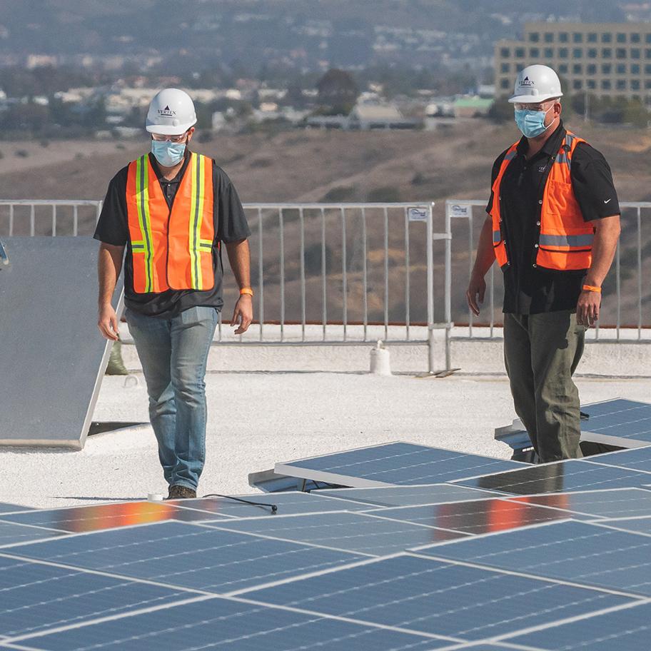 Two men in reflective vests inspect solar panels