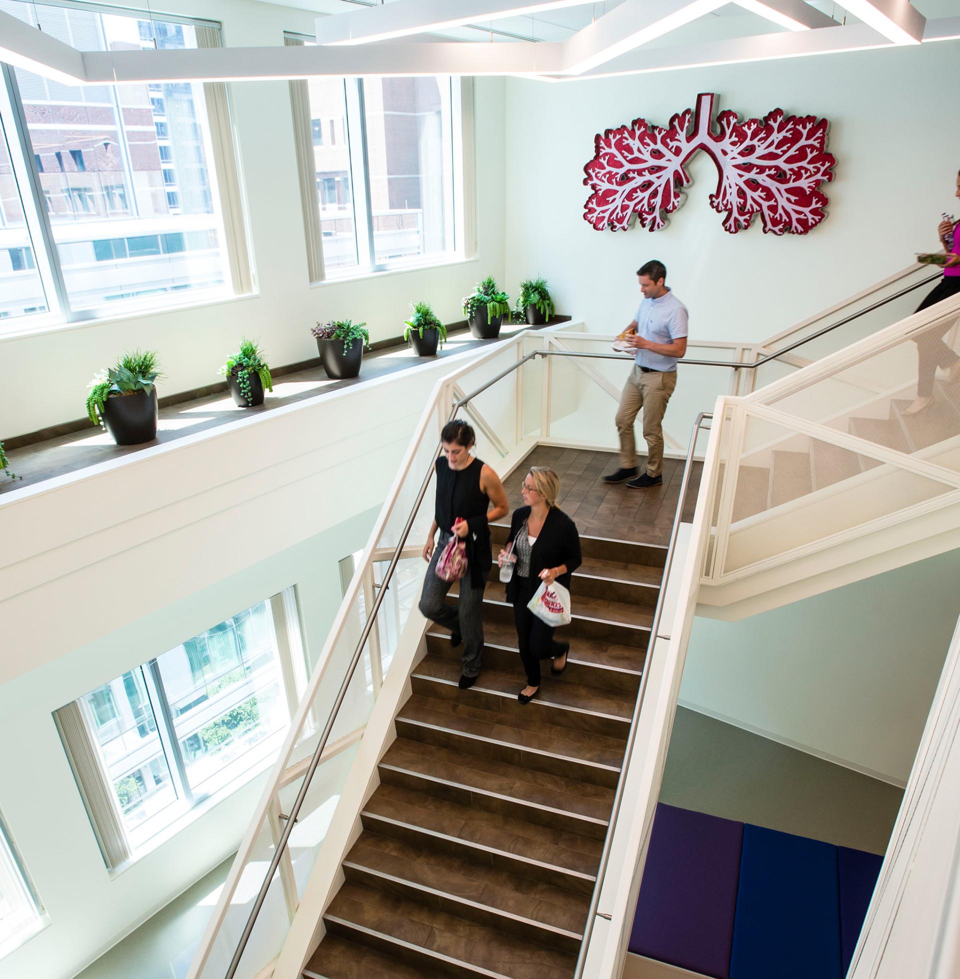 employees at Vertex headquarters walking down staircase