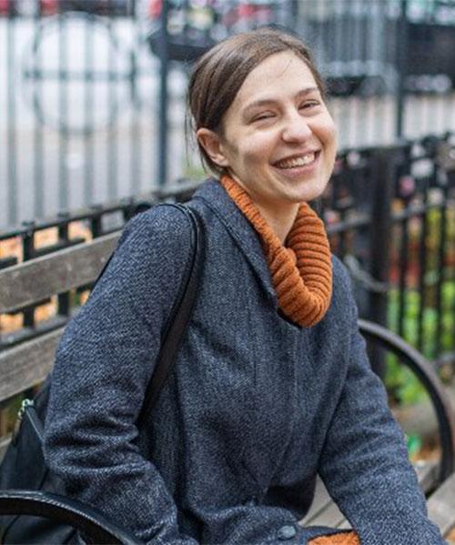 An image of Jordan Gass-Pooré smiling on a park bench