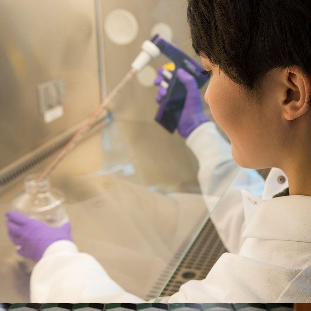 A female Vertex scientist works under the hood on an experiment