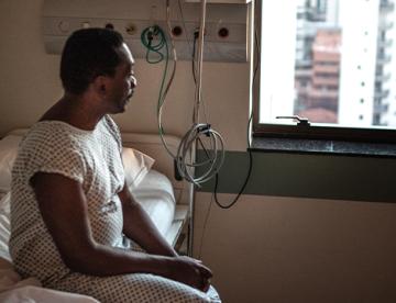 An image of a man sitting in a hospital bed staring out of a window