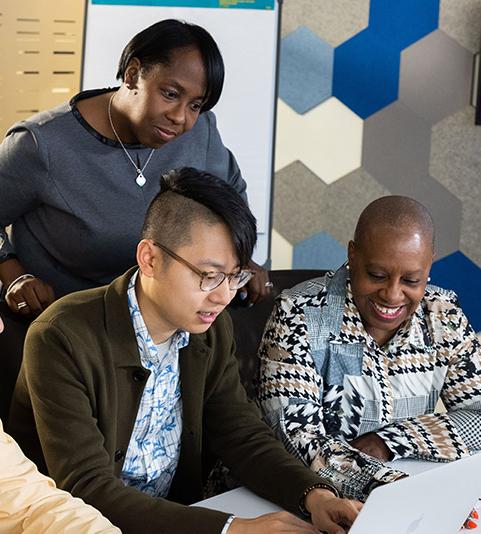 A group of 4 Vertex employees viewing content on a laptop