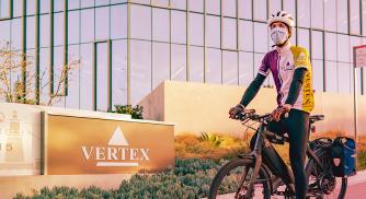 A Vertex employee rides a bicycle outside a Vertex office