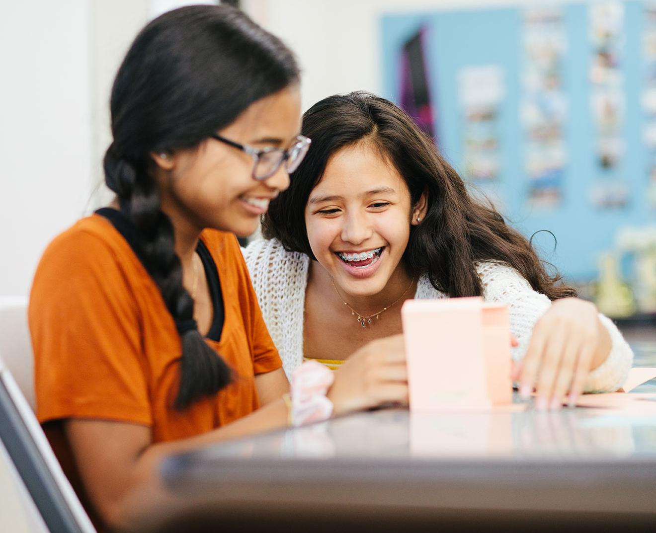 Two girls laughing and working on a project together