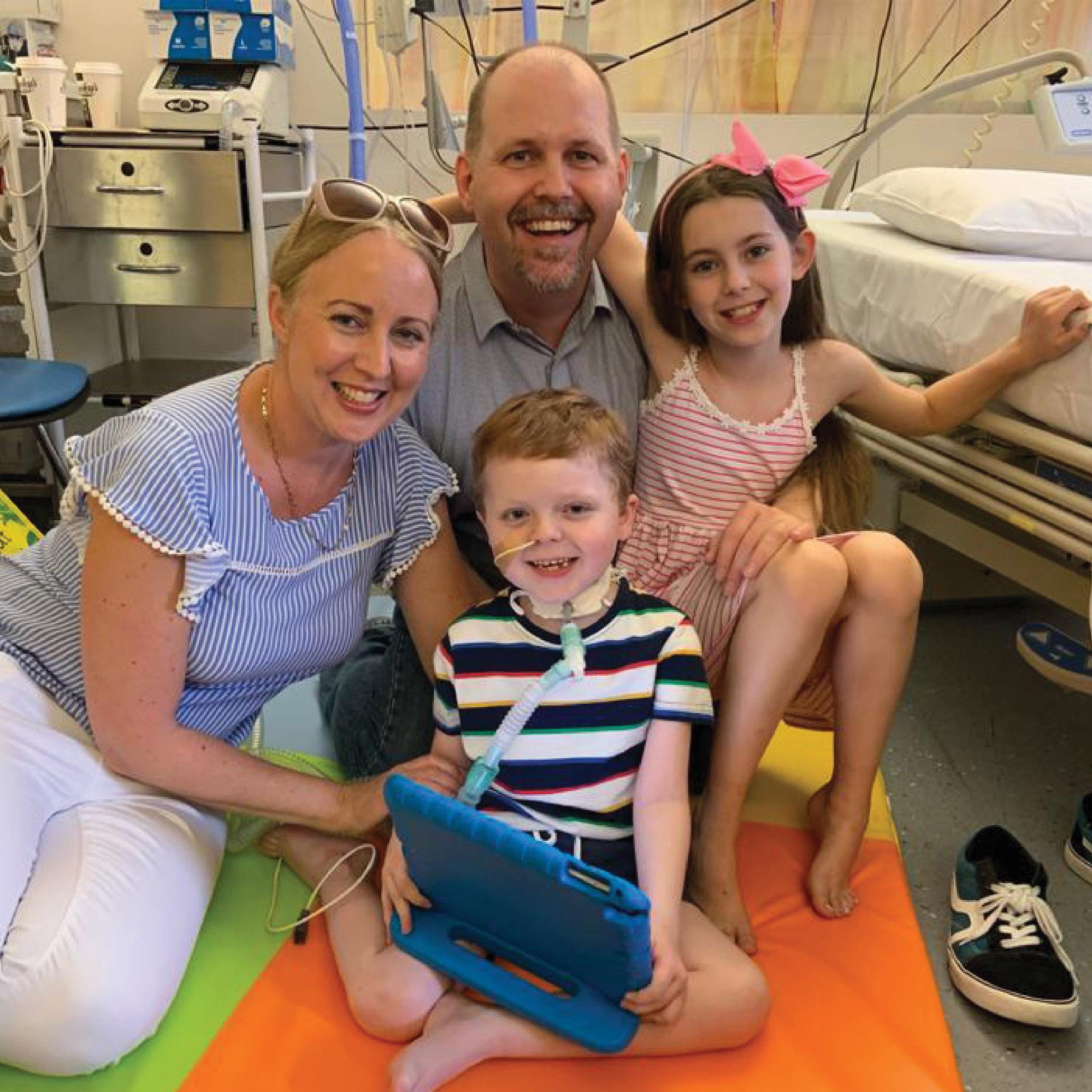 A mother, father, daughter and son smiling in a hospital room