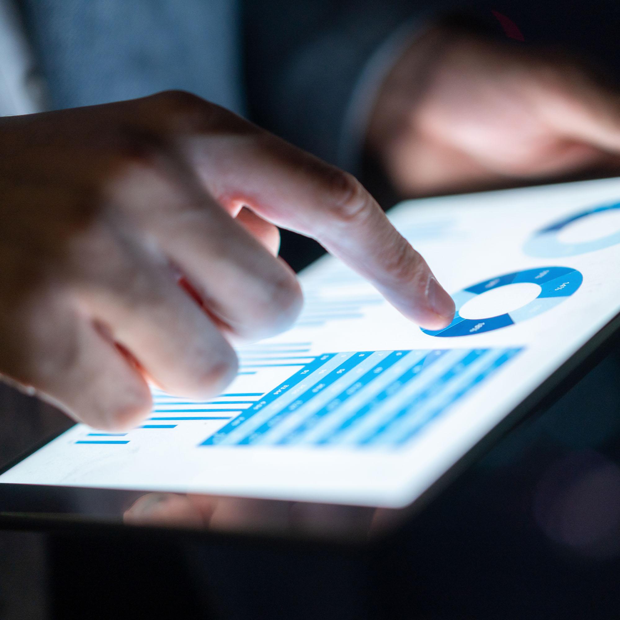 A close up of hands interacting with data on a tablet