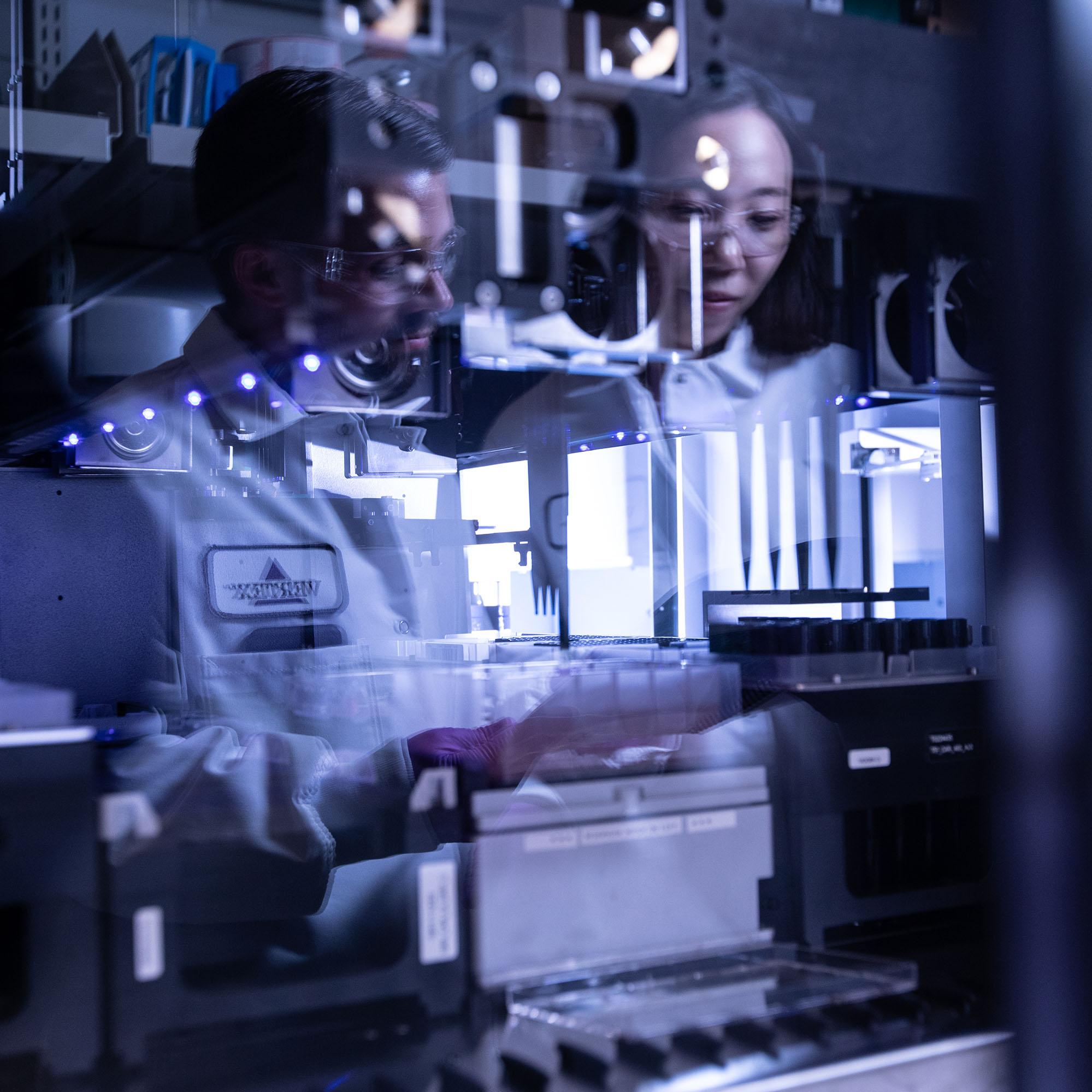 a reflection of two scientists in a lab window