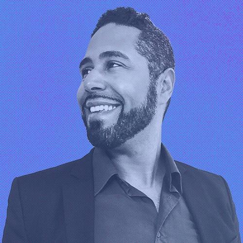 An image of Damian Sanchez looking to the left and smiling. The image has a blue overlay on it.