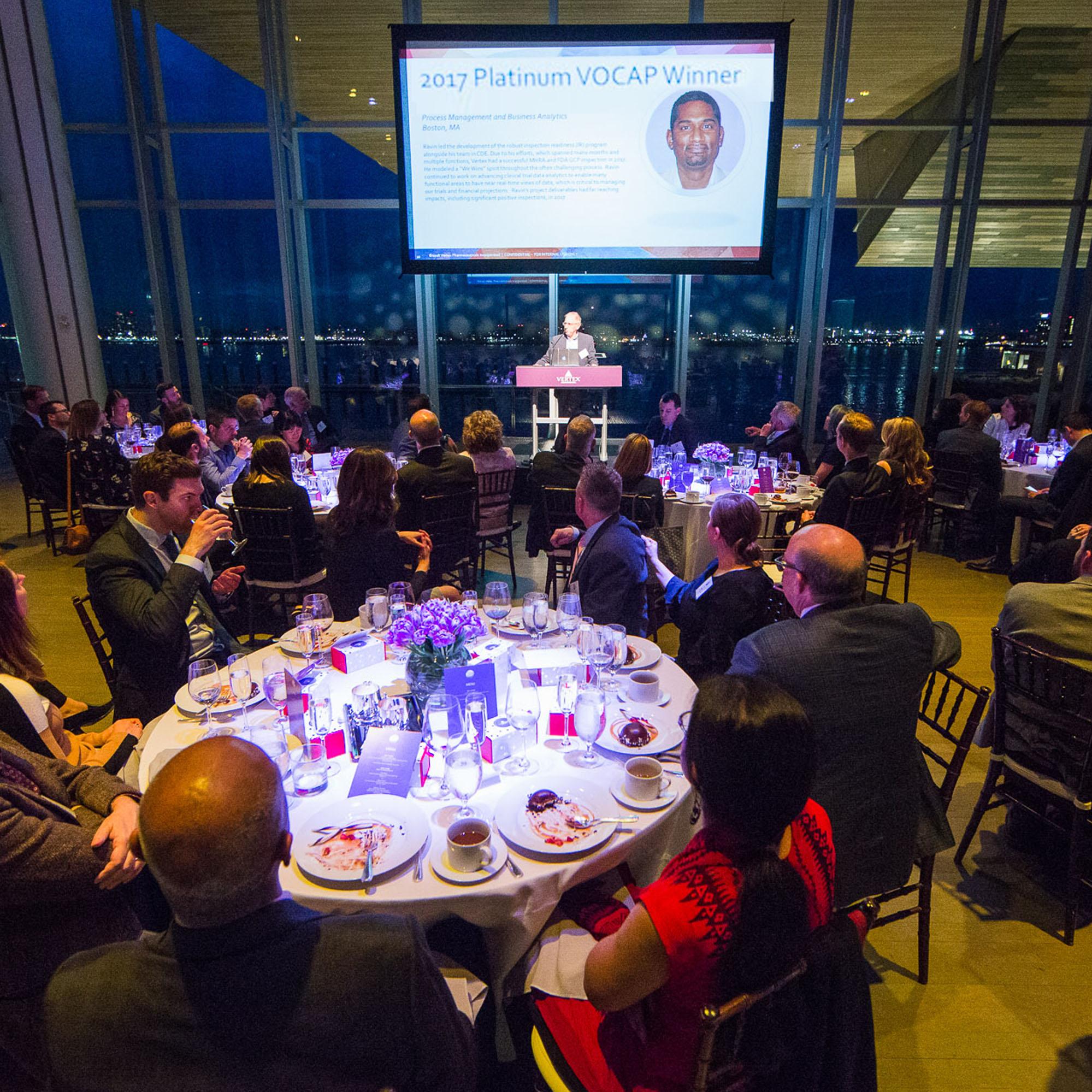 Employees sitting at tables at a Vertex award ceremony