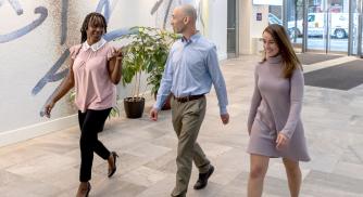 Three Vertex employees walking through the Vertex lobby in Boston